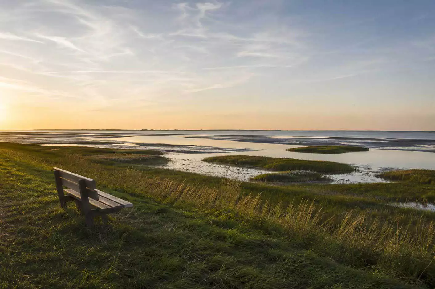 Ruhige Bank am Deich mit Blick über das Wattenmeer bei Sonnenuntergang auf Nordstrand